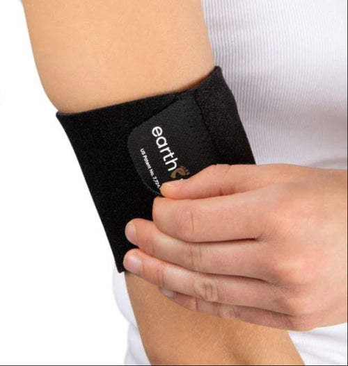 Black Earthing grounding arm band brace with Earthing logo against black, wrapped around someone's arm.